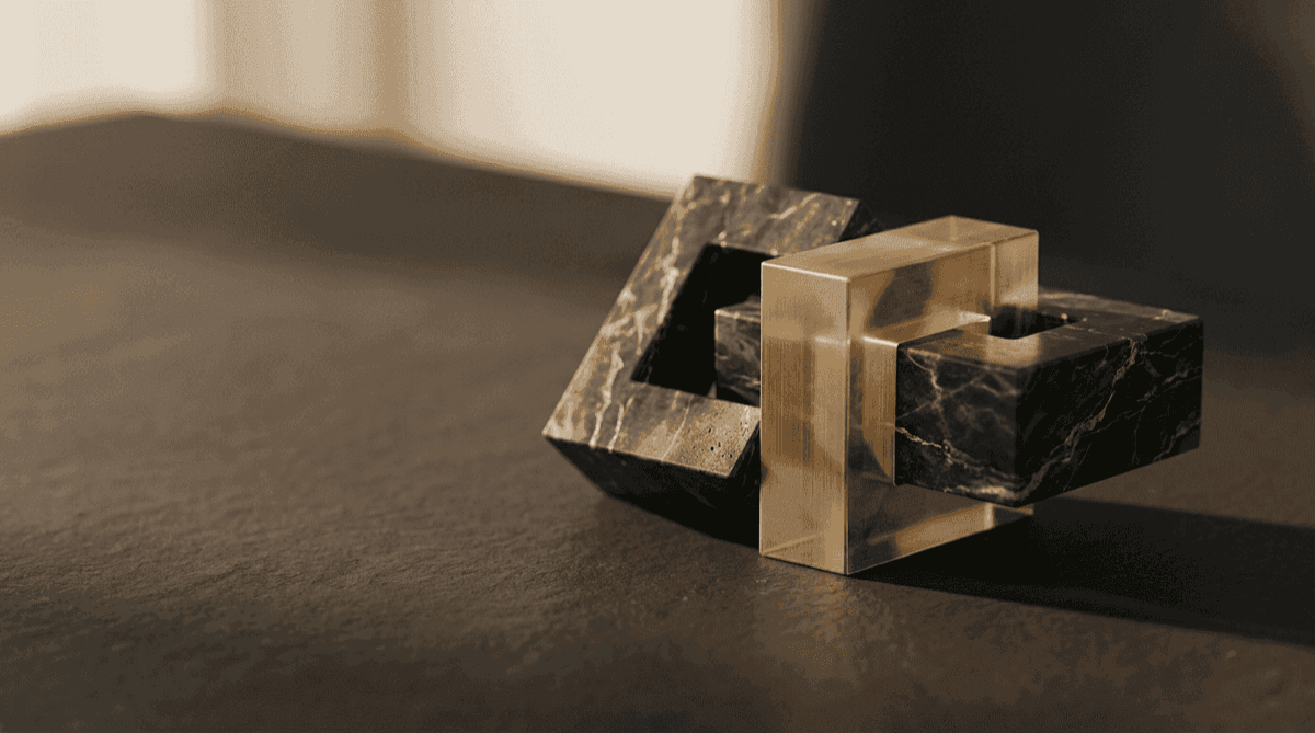 Abstract illustration for IFRS 18: interlocking marble and translucent amber frames on a dark surface, suggesting a new structure for presenting the same figures